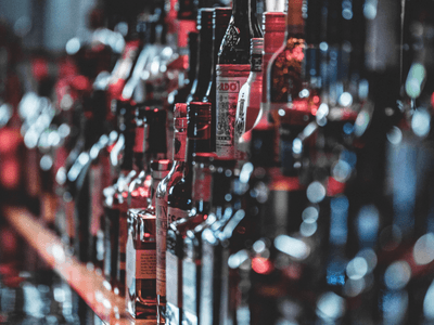 A blurred bar shelf filled with various bottles of liquor and spirits